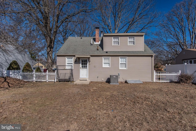 rear view of property with a yard, cooling unit, fence, and a chimney