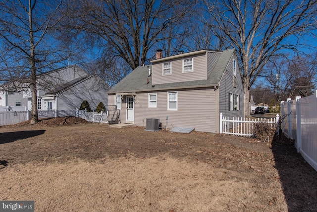 rear view of house featuring central AC, a shingled roof, a chimney, and a fenced backyard