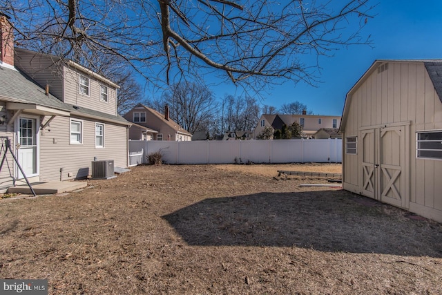 view of yard featuring an outbuilding, a shed, a fenced backyard, and central air condition unit