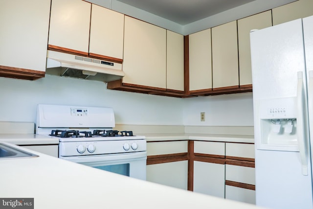 kitchen with white appliances, under cabinet range hood, and light countertops