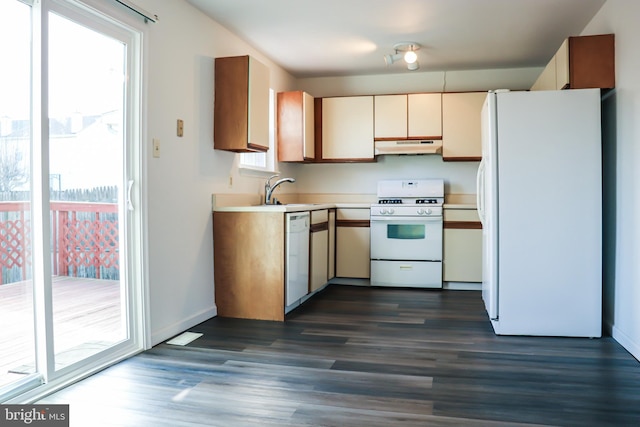 kitchen featuring white appliances, a sink, under cabinet range hood, and dark wood-style flooring