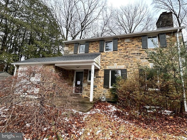 view of front facade featuring stone siding and a chimney