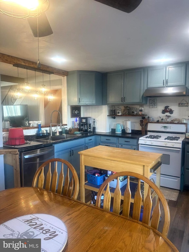 kitchen featuring white gas stove, under cabinet range hood, dishwasher, tasteful backsplash, and dark countertops