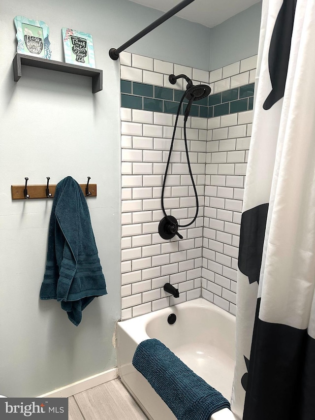 bathroom with shower / bath combination with curtain, wood finished floors, and baseboards