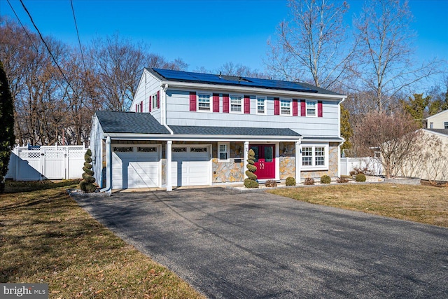 view of front facade featuring fence, stone siding, driveway, a gate, and a front yard