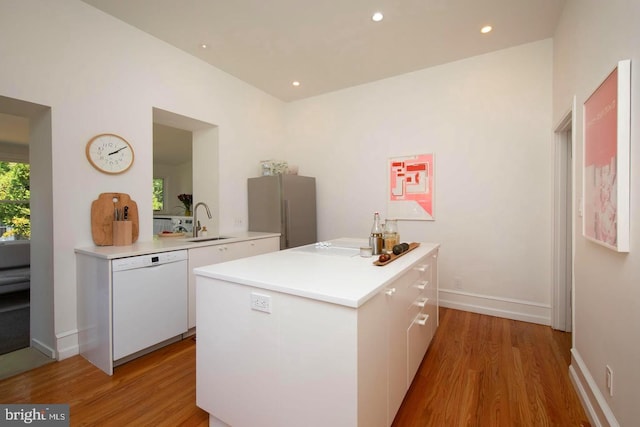 kitchen with light wood-style flooring, a sink, white cabinetry, freestanding refrigerator, and dishwasher