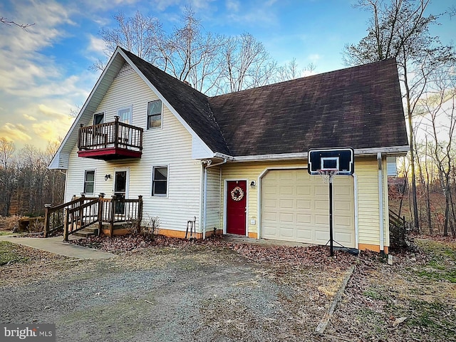 view of front of property with a balcony, driveway, a garage, and a shingled roof