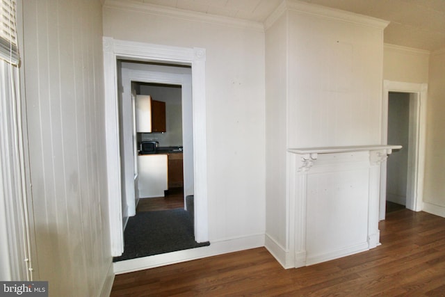 hall featuring wood finished floors, baseboards, and ornamental molding