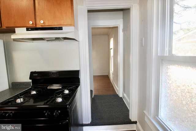 kitchen featuring under cabinet range hood, black gas stove, and brown cabinetry