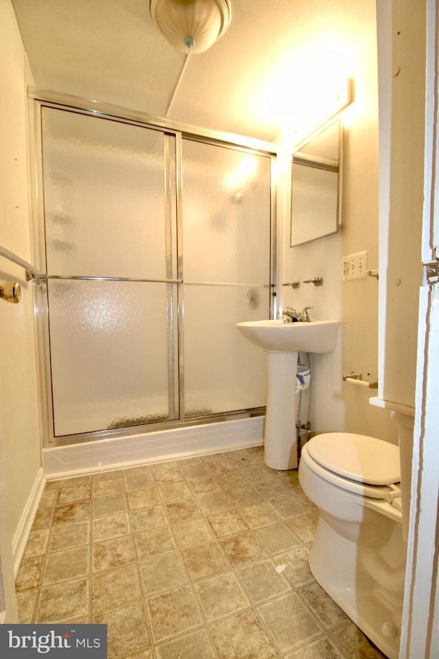 bathroom featuring toilet and a stall shower