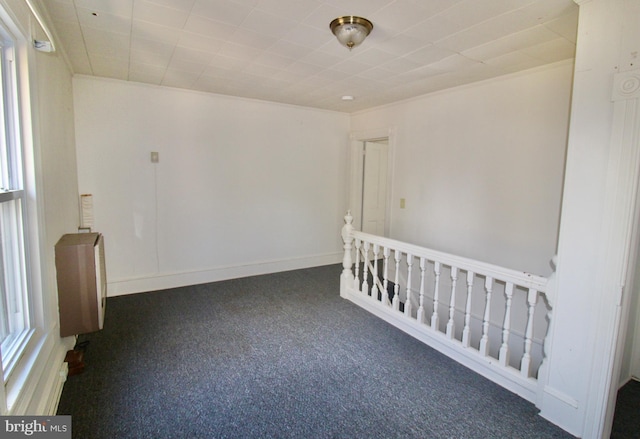 spare room with baseboards, carpet, and radiator heating unit