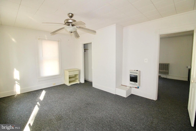 interior space featuring ornamental molding, heating unit, dark carpet, baseboards, and ceiling fan