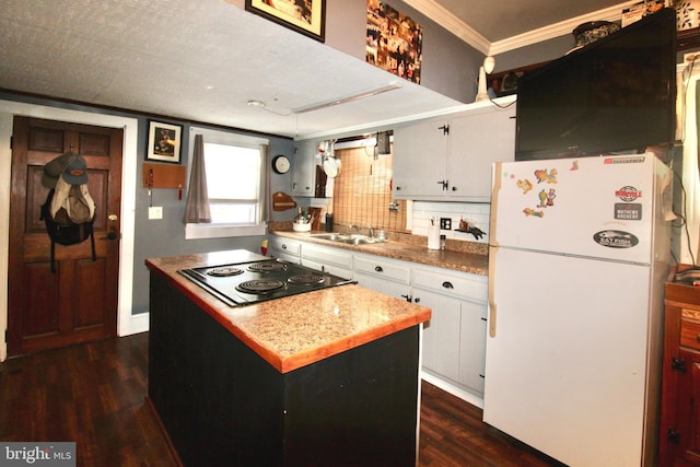 kitchen with stovetop, freestanding refrigerator, dark wood-type flooring, white cabinetry, and backsplash