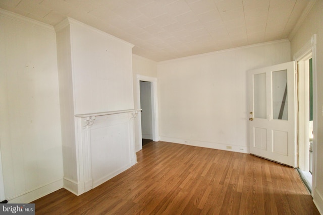 spare room featuring baseboards, wood finished floors, and ornamental molding