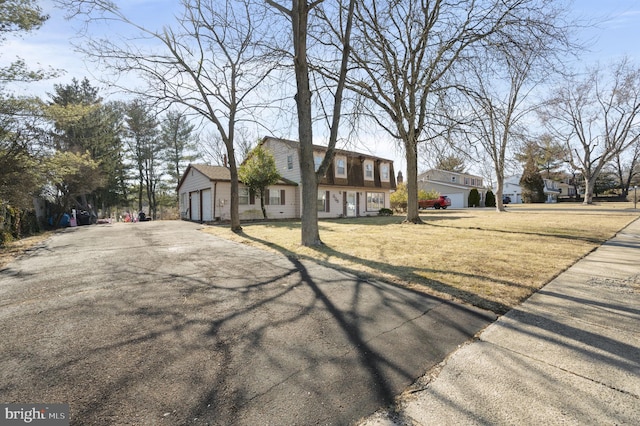 view of front facade with a garage, a front lawn, and aphalt driveway