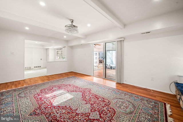 spare room featuring visible vents, beamed ceiling, and wood finished floors