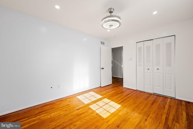 unfurnished bedroom featuring recessed lighting, a closet, visible vents, and wood finished floors