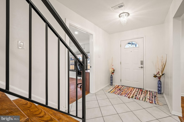 foyer entrance with light tile patterned floors, stairs, visible vents, and baseboards