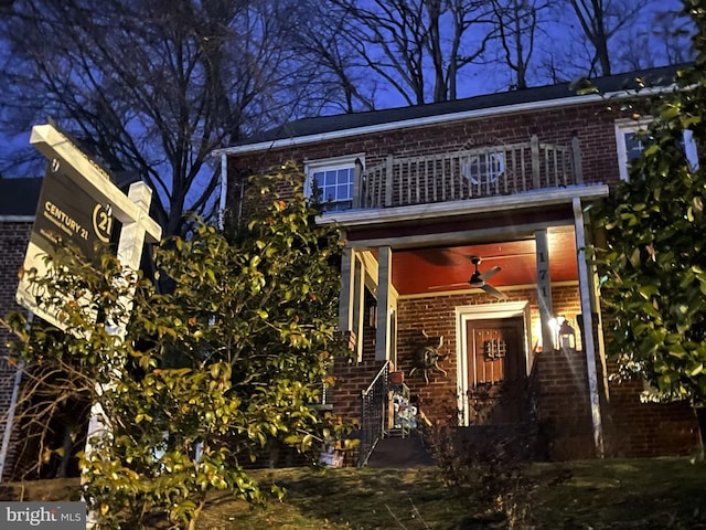 view of front facade featuring brick siding, ceiling fan, and a balcony