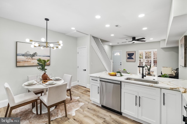 kitchen featuring white cabinets, dishwasher, a peninsula, light wood-style floors, and a sink