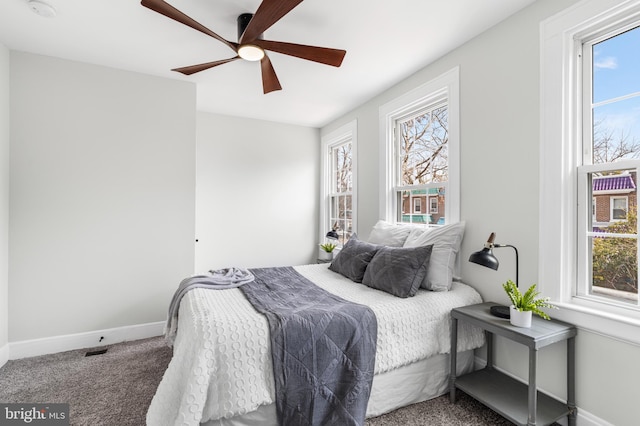 bedroom with carpet floors, multiple windows, ceiling fan, and baseboards