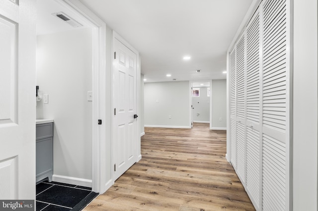 corridor featuring baseboards, light wood-style flooring, visible vents, and recessed lighting