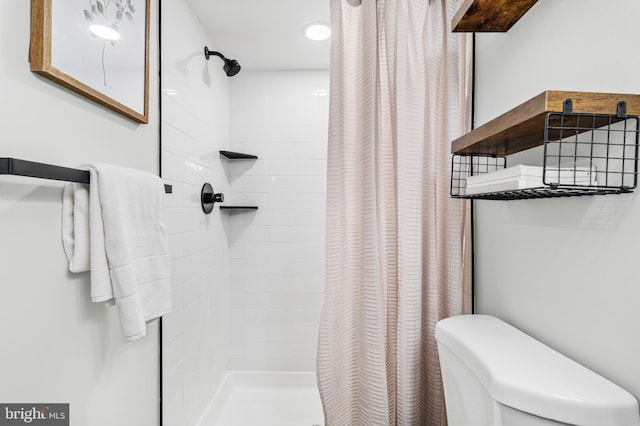 bathroom featuring tiled shower and toilet