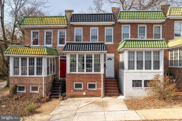 view of front of house with entry steps, brick siding, mansard roof, and a tiled roof