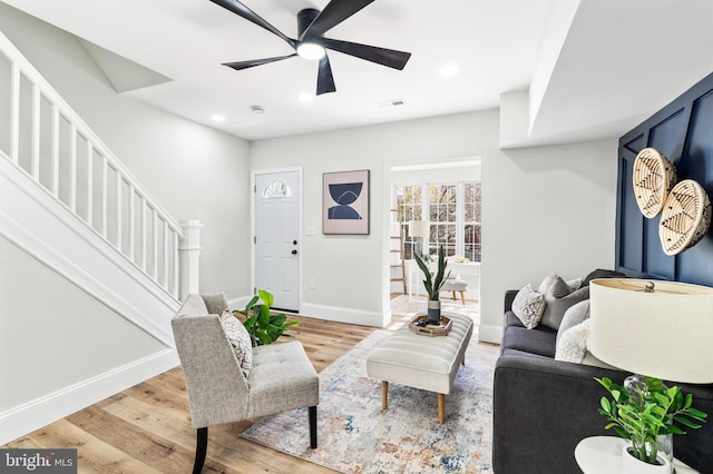 living room featuring baseboards, visible vents, stairway, light wood-type flooring, and recessed lighting