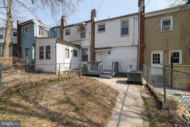 rear view of property featuring central AC and fence