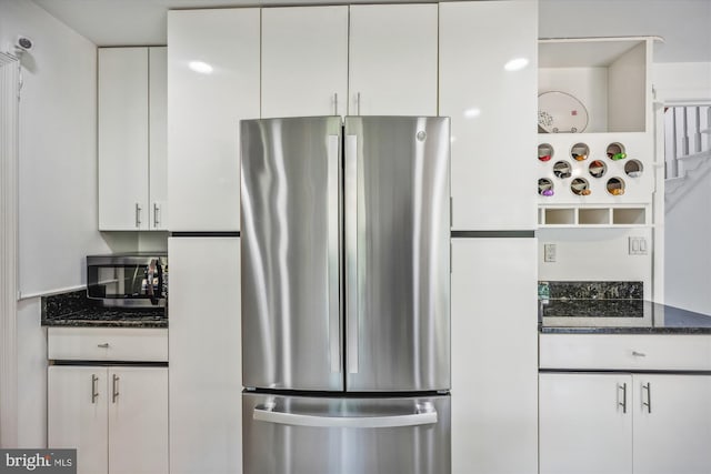 kitchen with appliances with stainless steel finishes, white cabinetry, and dark stone countertops