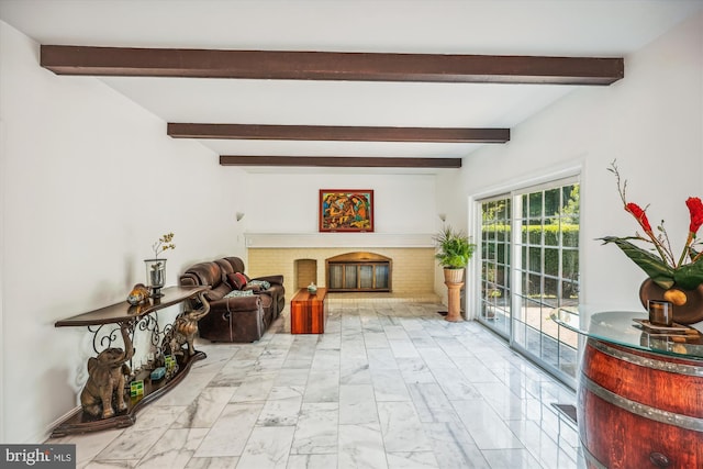 living area featuring marble finish floor, a fireplace, and beamed ceiling