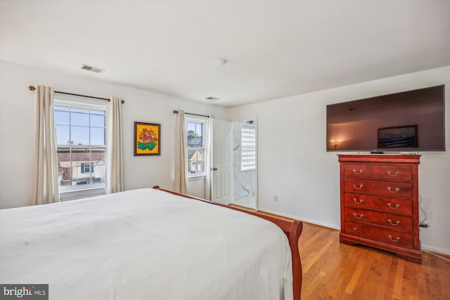 bedroom with baseboards, multiple windows, visible vents, and wood finished floors