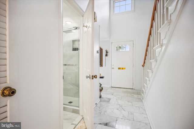 entrance foyer with marble finish floor, stairway, and baseboards