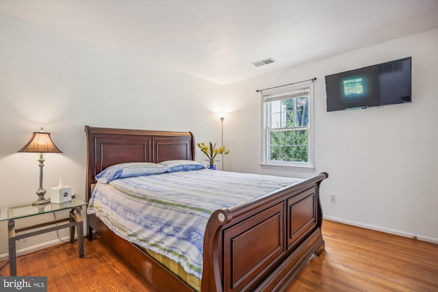 bedroom with wood finished floors, visible vents, and baseboards