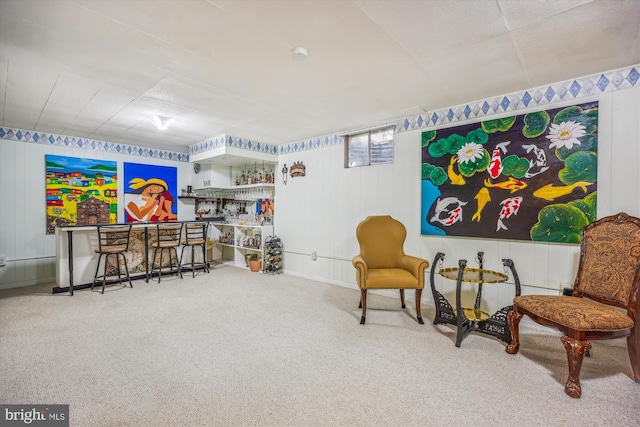 sitting room featuring a bar and carpet flooring