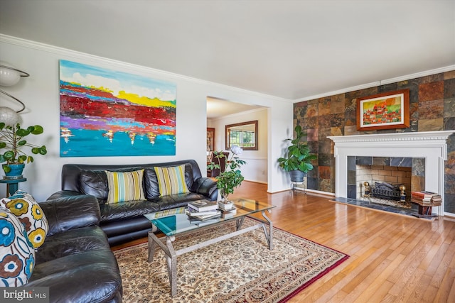 living area featuring wood-type flooring, a fireplace, and crown molding