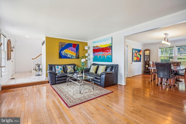 living area featuring an inviting chandelier, wood-type flooring, stairway, and crown molding