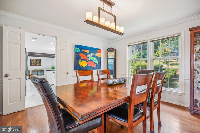 dining area featuring baseboards, crown molding, an inviting chandelier, and hardwood / wood-style flooring