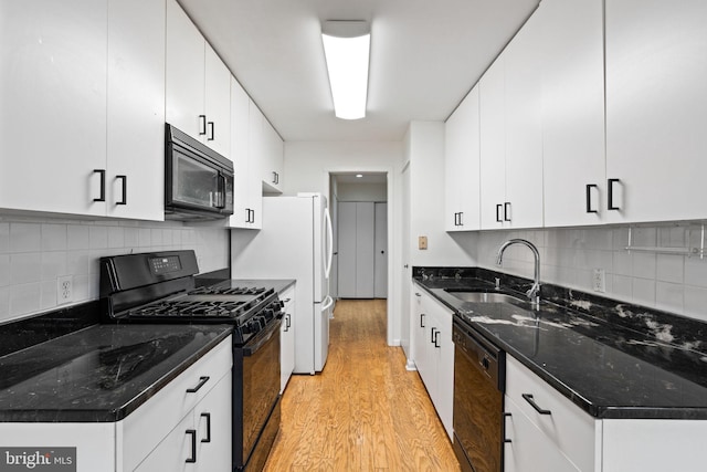 kitchen featuring white cabinets, black appliances, light wood finished floors, and a sink