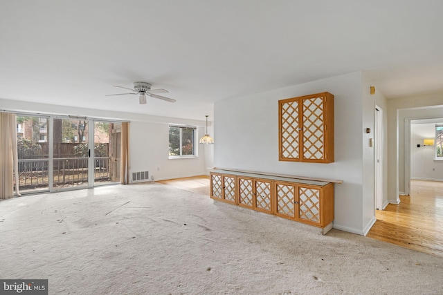 unfurnished room featuring carpet floors, a ceiling fan, visible vents, and baseboards