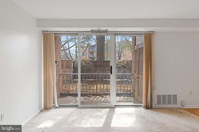 doorway with baseboards, visible vents, and carpet flooring