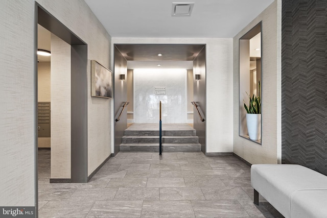 hall with baseboards, stairway, visible vents, and wallpapered walls