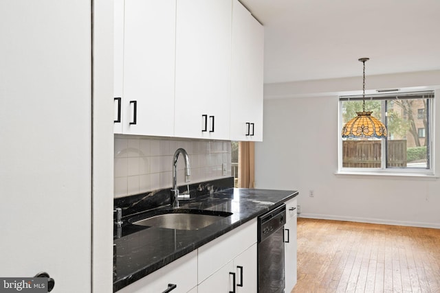 kitchen with tasteful backsplash, dishwasher, dark stone countertops, light wood-type flooring, and a sink