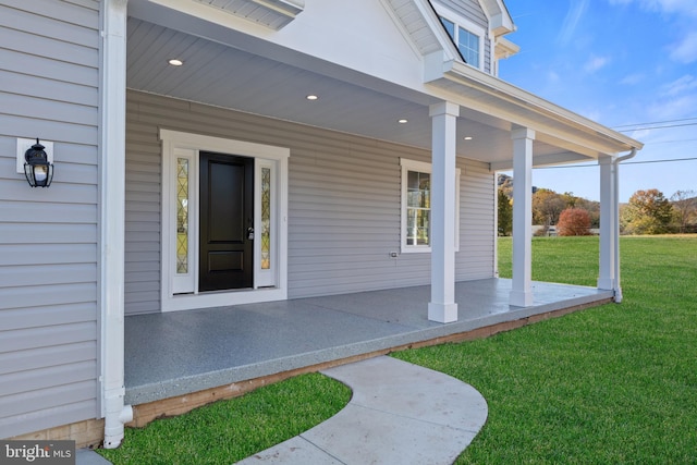 view of exterior entry with a porch and a lawn