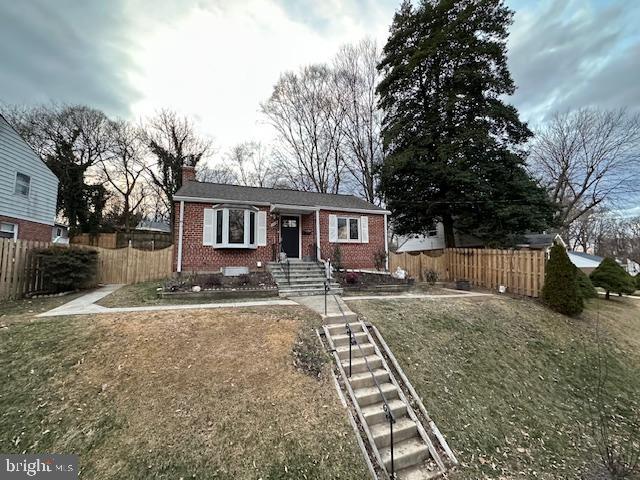 view of front of home with fence, brick siding, and a chimney