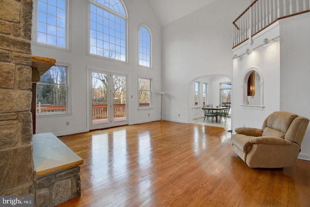 living area featuring arched walkways, baseboards, and wood finished floors