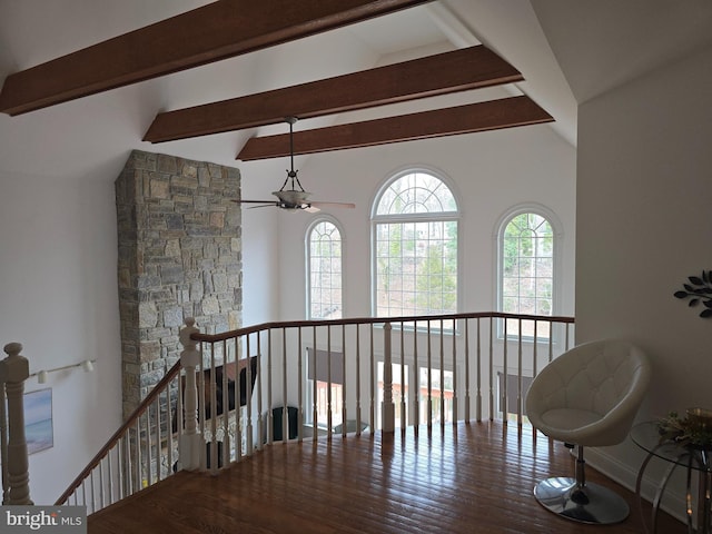 corridor featuring an upstairs landing, lofted ceiling with beams, and wood finished floors