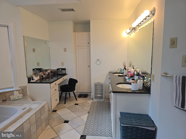 bathroom with tile patterned flooring, visible vents, tiled bath, and double vanity