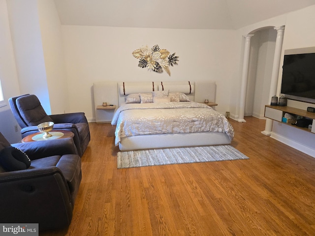 bedroom featuring decorative columns, baseboards, and wood finished floors